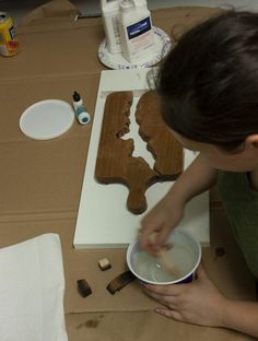 a woman is painting wooden cutouts on the table with paint and wood shaving tools