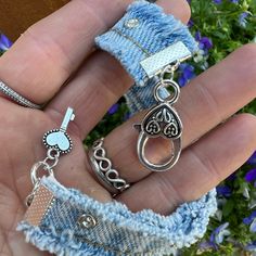 two pieces of jewelry are in the palm of someone's hand with blue flowers behind them