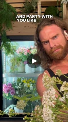 a man standing in front of a refrigerator filled with lots of flowers next to plants