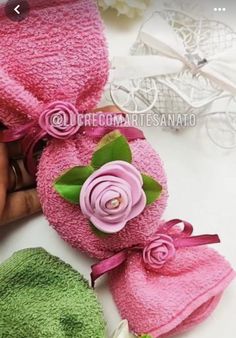 two towels with pink and green flowers on them, one being rolled up into a flower