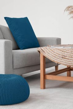 a living room with a gray couch, blue pillows and a coffee table in the corner