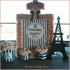 a chanel party with pink flowers and black and white boxes in front of the eiffel tower