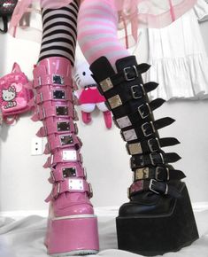 a pair of pink and black high heeled boots with spikes on the side, sitting next to a hello kitty doll