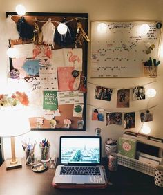 a laptop computer sitting on top of a wooden desk next to a lamp and pictures