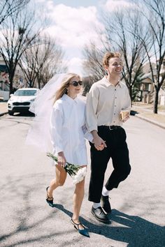 a man and woman walking down the street holding hands with each other while wearing sunglasses