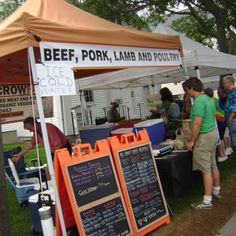 people are standing under a tent selling food