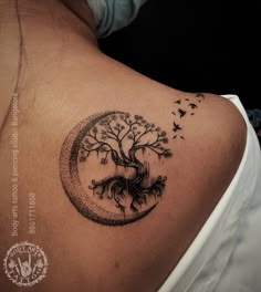 a woman's back with a tree and birds in the circle tattoo on it