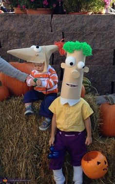 two children dressed up as cartoon characters sitting on hay with pumpkins in front of them