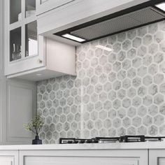 a kitchen with white cabinets and marble backsplash, an oven hood over the stove