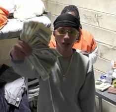 a young man wearing sunglasses and holding money