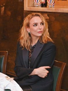 a woman sitting at a table with her arms crossed and looking off to the side