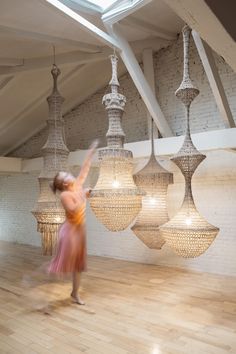 a woman is dancing in an empty room with chandeliers hanging from the ceiling