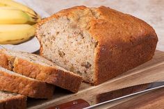 a loaf of banana bread sitting on top of a cutting board next to some bananas