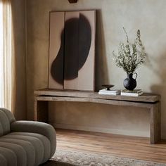 a living room with a couch, table and vase on the wall next to it