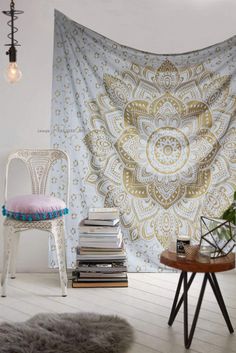 a chair and table in front of a wall with a large tapestry hanging on it