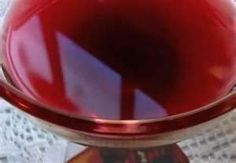 a red glass bowl sitting on top of a white doily next to a piece of paper