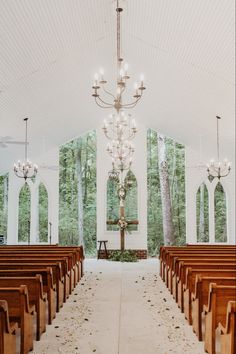 an empty church with rows of pews and chandeliers hanging from the ceiling