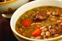 a white bowl filled with beans and carrots next to another bowl full of soup