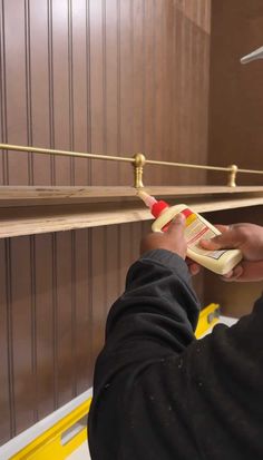 a man is painting the wall with brown paint and yellow piping tape on it