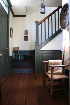 a chair sitting in the middle of a room next to a stair case and door