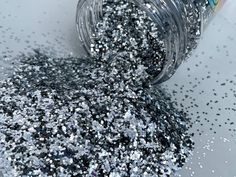 a jar filled with silver glitter on top of a white tablecloth covered in confetti