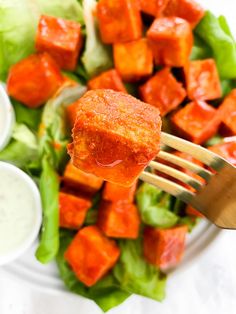 a fork with some food on it that is being held up to the camera over a salad