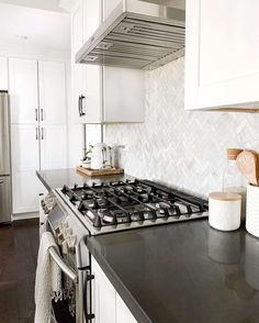 a stove top oven sitting inside of a kitchen next to white cabinets and counter tops