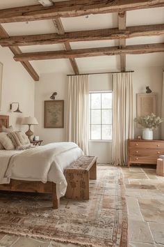 a large bed sitting under a wooden beam in a bedroom next to a window with drapes