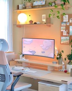 a desk with a computer monitor and plants on it