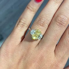 a close up of a person's hand with a ring on it and a yellow diamond in the middle