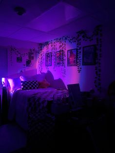 a bedroom with purple lighting and pictures on the wall above the bed, along with laptops