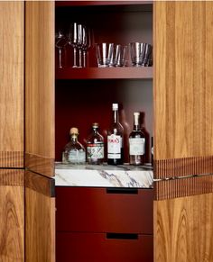 bottles and glasses are sitting on the counter in front of wooden cupboards with wine glasses