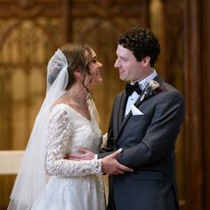 a bride and groom standing in front of the alter at their wedding ceremony, looking into each other's eyes