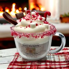 a hot chocolate drink with marshmallows and candy canes on top in front of a fireplace