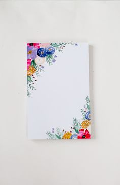 an empty notepad with colorful flowers on the front and back cover, against a white background