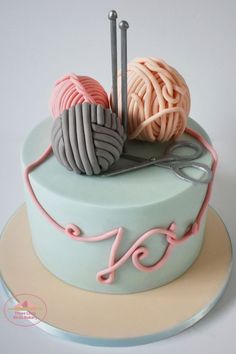 a cake decorated with yarn and knitting needles