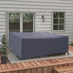 an outdoor patio with a table and chairs covered in a blue cover next to a house