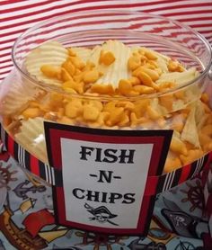 fish n chips in a glass bowl on top of a table with red and white striped cloth