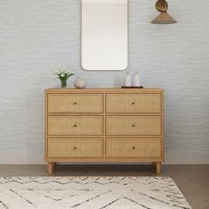 a wooden dresser with a mirror and vase on top of it in front of a blue wall