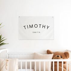 a teddy bear sitting in a white crib next to a sign that says, tommy