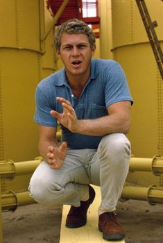 a man squatting down in front of some yellow piping pipes and holding his hands out