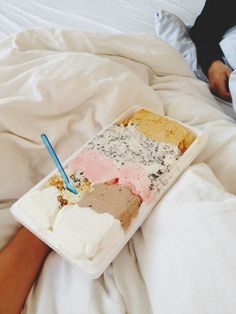 someone is laying in bed with an ice cream sundae