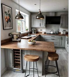 a kitchen with two stools and an island in the middle, surrounded by gray cabinets