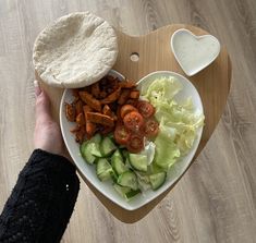 a person holding a heart shaped plate with food on it