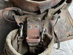 an old, worn out bucket is sitting on top of a wooden chair with straps around it