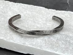 a silver bracelet sitting on top of a white piece of paper