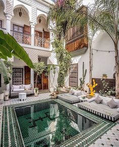 an indoor swimming pool in the middle of a courtyard with seating and potted plants