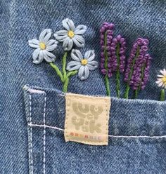 some flowers are sticking out of the back pocket of someone's jean jacket,