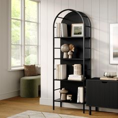 a black book shelf with books on top of it next to a chair and window