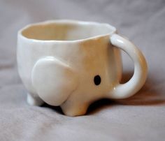 an elephant shaped coffee cup sitting on top of a bed